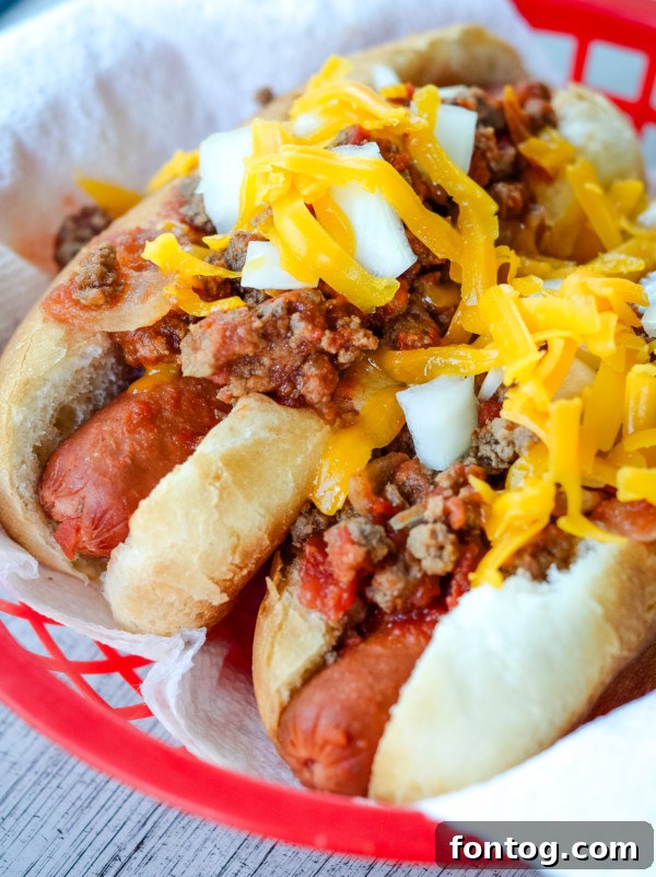 Hearty slow cooker chili dogs topped with cheese and onions, ready to be served