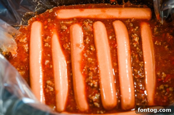 Close-up of chili simmering in a slow cooker with hot dogs