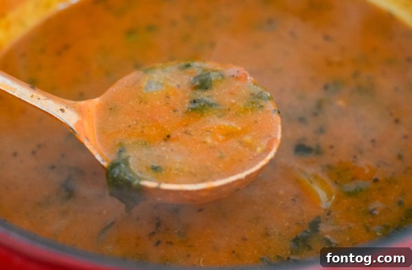 Two bowls of creamy tomato florentine soup on a wooden board.