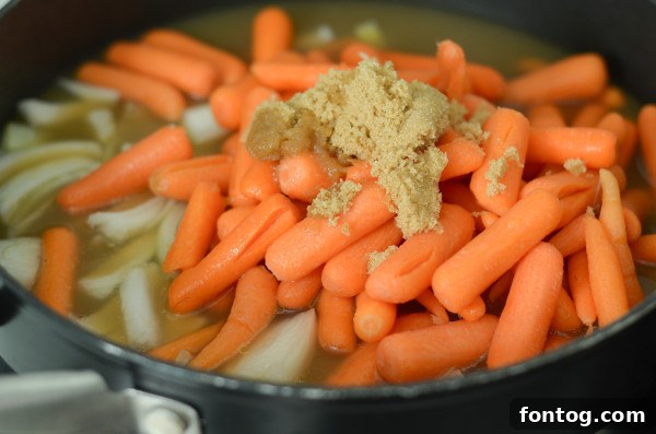 Ingredients laid out for making apple cider glazed carrots, including baby carrots, sweet onion, apple cider, brown sugar, and olive oil.
