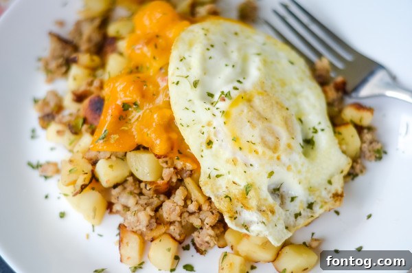 Savory Sausage, Egg, and Cheese Breakfast Hash 4 Cheesy Sausage and Egg Hash topped with a fried egg and a sprinkle of fresh herbs