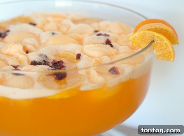 Overhead shot of a punch bowl filled with Cranberry Orange Punch, garnished with whole cranberries and orange slices.