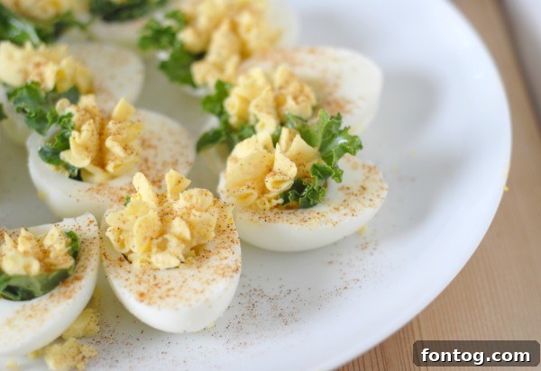 Close-up of a Kale Stuffed Deviled Egg, showing the vibrant green kale beneath the smooth, piped egg yolk filling.