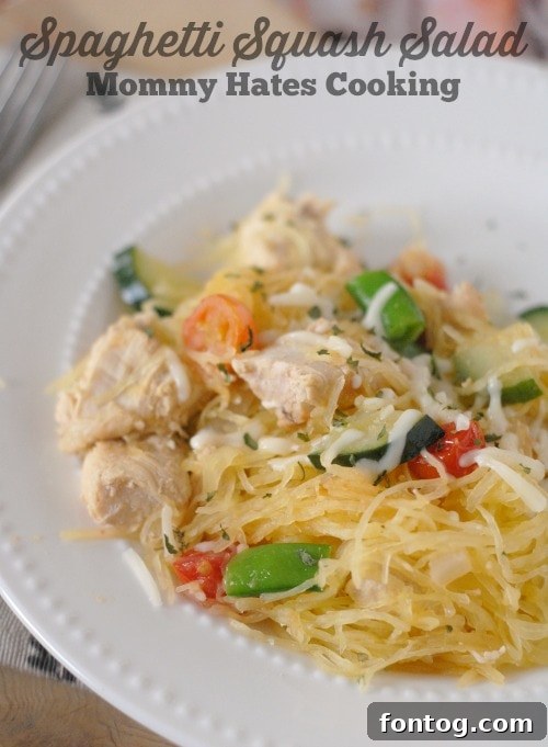 Freshly prepared Spaghetti Squash Salad in a bowl, showing strands of squash mixed with colorful vegetables like tomatoes, cucumbers, and peas.