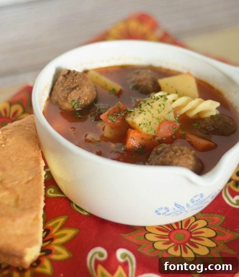 Hearty Slow Cooker Meatball Soup in a rustic bowl, garnished with fresh herbs