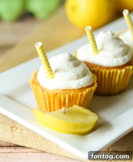 Freshly baked Strawberry Lemonade Cupcakes with swirls of whipped cream, garnished with lemon slices and small yellow straws, ready to be served.