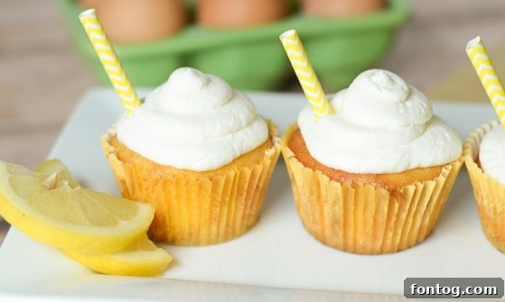 Two Strawberry Lemonade Cupcakes adorned with a swirl of pink frosting, white sprinkles, and a small decorative straw, suggesting a refreshing and fun dessert.