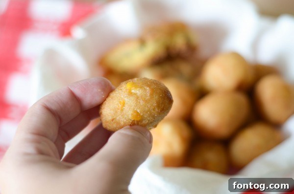 A close-up of crispy catfish nuggets and hush puppies nestled in a red checkered basket, hinting at the delicious textures.