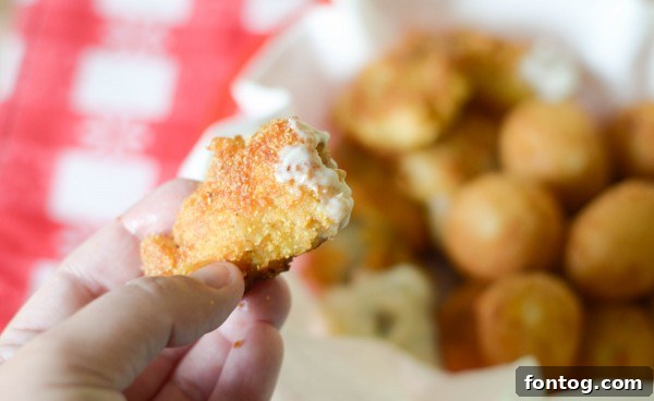 Close-up of a red paper basket filled with a generous serving of crispy catfish nuggets and golden hush puppies.