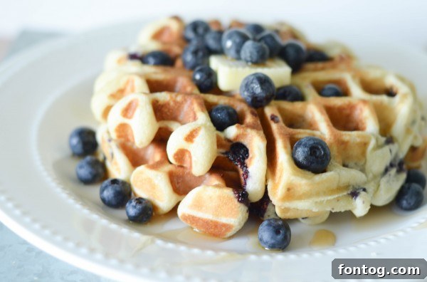 Close-up of golden Gluten-Free Blueberry Waffles stacked on a plate