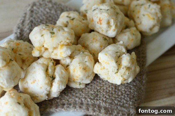 A batch of baked gluten-free cheddar bay biscuits cooling on a wire rack, freshly glazed.