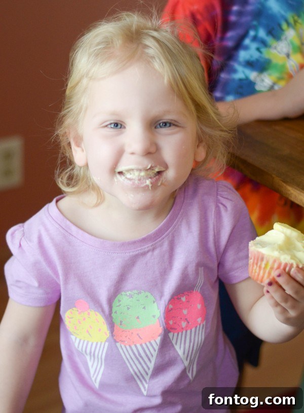 Fresh Bloom Cupcakes 12 A close-up of a child's hand eagerly reaching for a freshly baked Spring Cupcake, highlighting the irresistible appeal of the sweet treats.