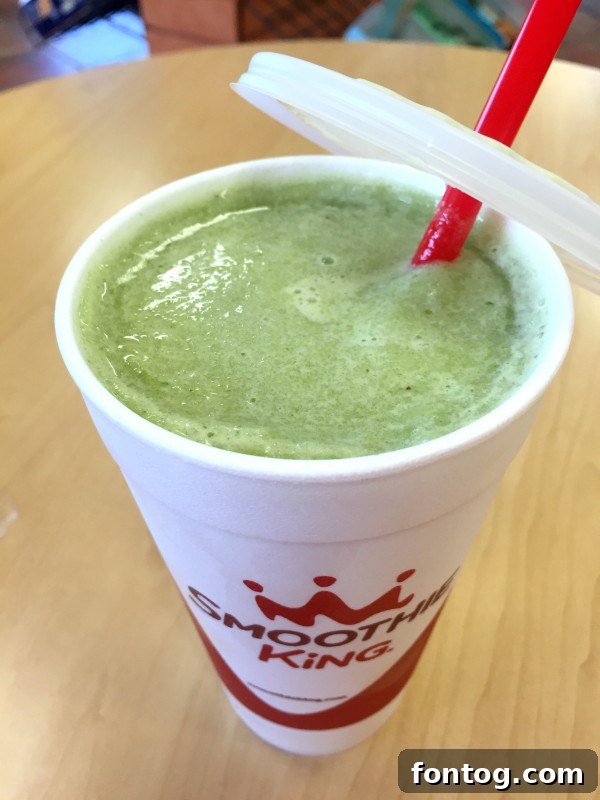 Enjoying a refreshing Apple Kiwi Kale Smoothie at Smoothie King, promoting wellness with #BlendMoreVeggies.