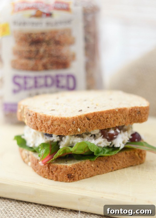 A freshly made Rosemary Chicken Salad sandwich on Harvest Blends bread, cut in half and ready to eat.