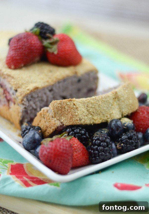 A selection of fresh berries – strawberries, blueberries, and blackberries – next to a loaf of Berry Oatmeal Bread.