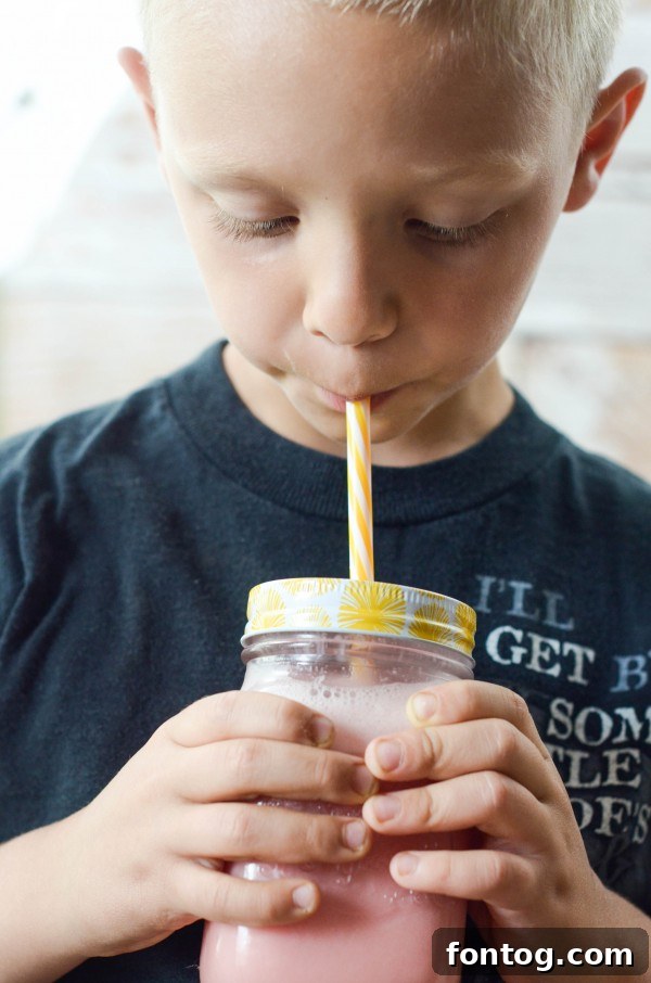 Hand holding a glass of Watermelon Smoothie with a straw