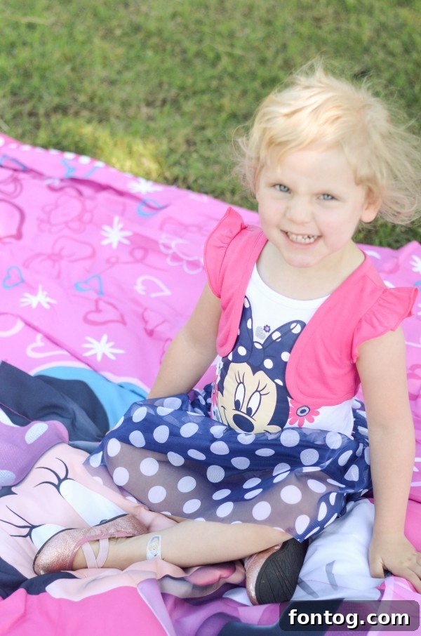 Happy little girl in a Minnie Mouse dress laughing and playing outdoors, enjoying a Mother's Day picnic. #MotherDaughterTime #OutdoorFun