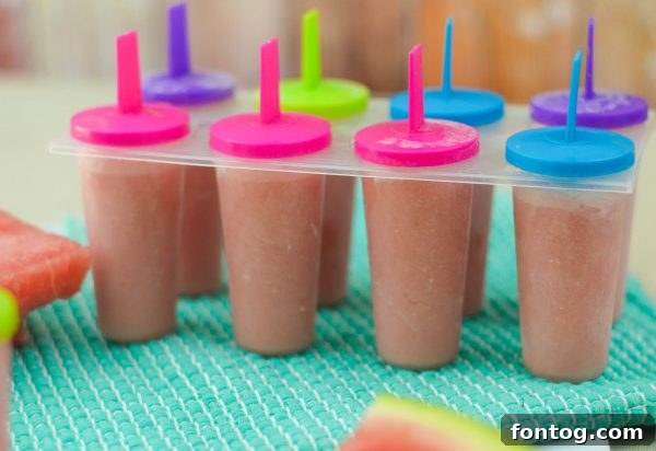 A close-up view of a single Watermelon Yogurt Pop, highlighting its creamy, icy texture, perfect for a refreshing break.