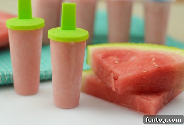 A hand holding a Watermelon Yogurt Pop, emphasizing the refreshing enjoyment on a hot summer day.