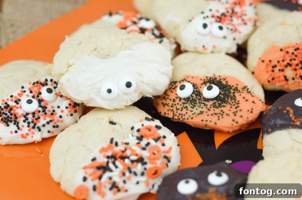Spooky Sugar Cookies - Close-up of a stack of decorated Halloween sugar cookies with orange and black candy melts and googly eyes.