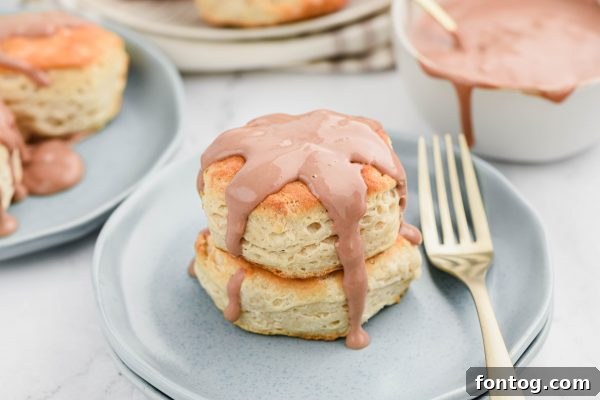Hand pouring chocolate gravy over a warm biscuit.