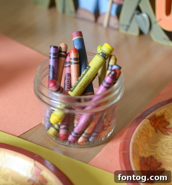 A child's hand placing a sticker on a small pumpkin at the kids' Thanksgiving table.