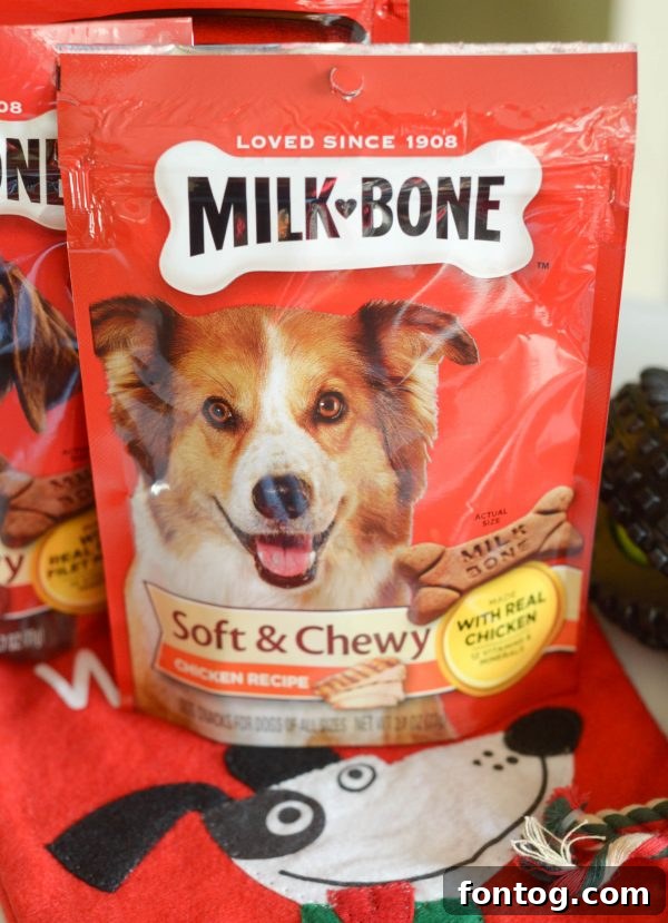 A festive red and white dog stocking hanging, filled to the brim with various dog treats and a toy