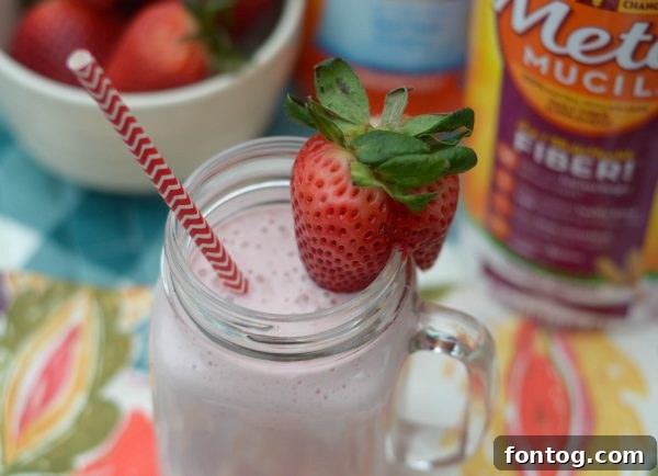 Close-up of a strawberry smoothie parfait layered with yogurt, fruit, and oats, topped with Meta.