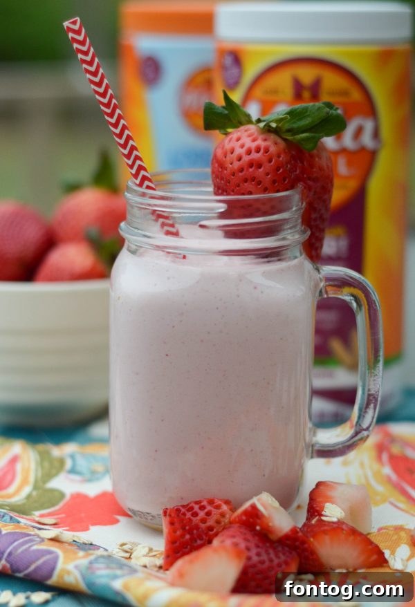 Strawberry smoothie parfait in a mason jar, topped with oats and a spoon, ready for a healthy meal.