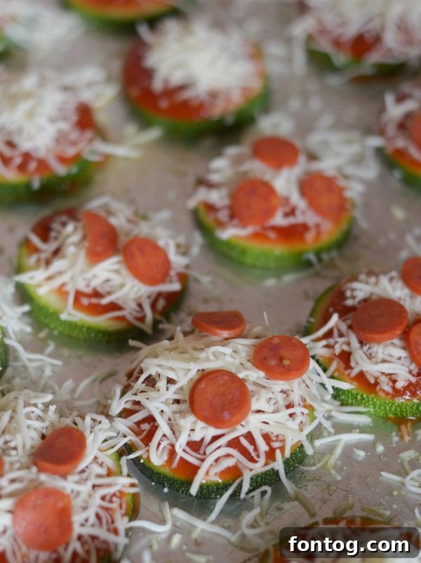 Zucchini Pizza Bites being prepared with olive oil spray and garlic salt.