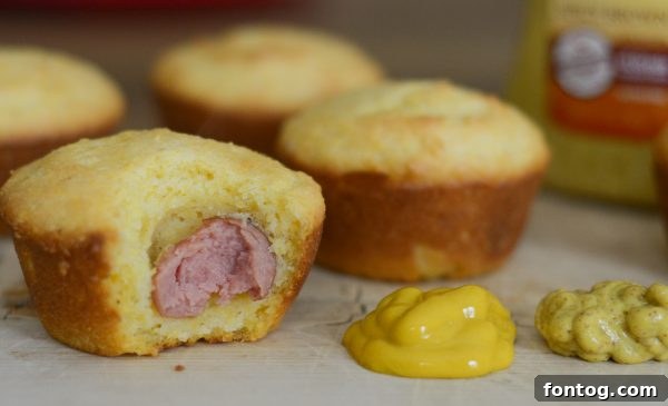 Freshly baked Corn Dog Muffins with a hot dog piece peeking out.