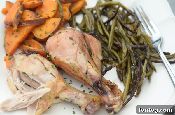 Raw chicken drumsticks, sweet potato cubes, and green beans seasoned with olive oil and rosemary on a single sheet pan
