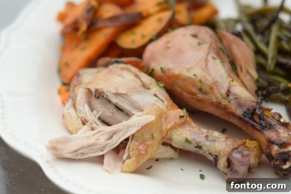 A delicious serving of Sheet Pan Rosemary Chicken with golden roasted sweet potatoes and green beans on a white plate