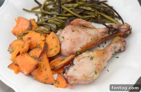 Large overhead shot of a perfectly roasted sheet pan meal with rosemary chicken drumsticks, sweet potatoes, and green beans