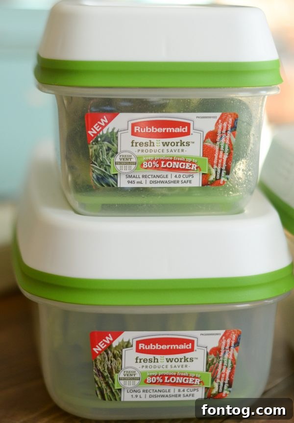 Variety of fresh fruits and vegetables like apples, oranges, and greens stored in a kitchen using Rubbermaid FreshWorks containers, promoting organization.