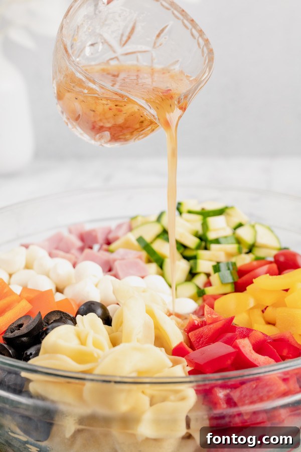 Mixing bowl filled with cooked tortellini, chopped bell peppers, tomatoes, and zucchini