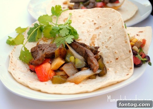 Close-up of cooked steak fajitas with vibrant peppers and onions, ready to be served in a cast iron skillet.
