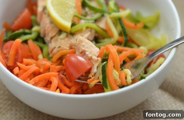 A close-up of a delightful Green Giant Veggie Spiral bowl with grilled salmon, lemon slices, and fresh herbs, showcasing a quick and healthy meal prepared in minutes.