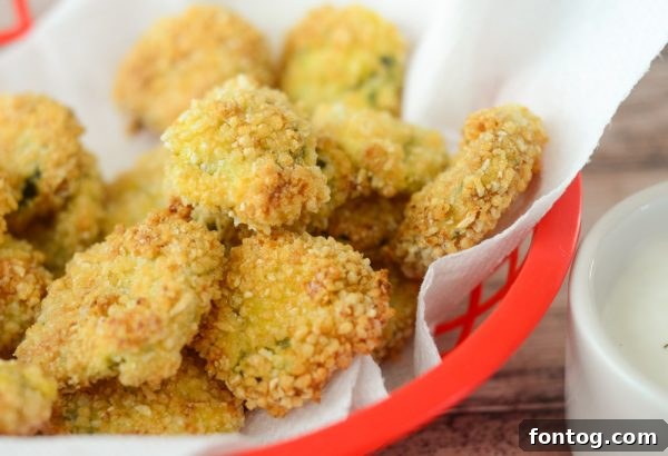 Close-up of golden-brown Air Fryer Fried Pickles on a plate with ranch dipping sauce, showcasing their crispy texture.