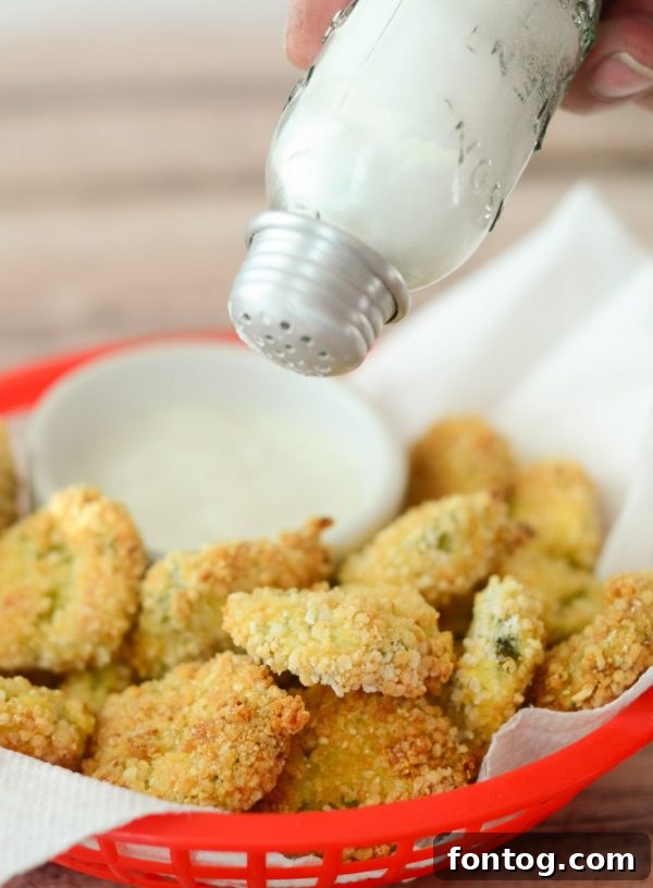 A basket of freshly air-fried pickles, golden and crispy, ready to be removed from the air fryer.