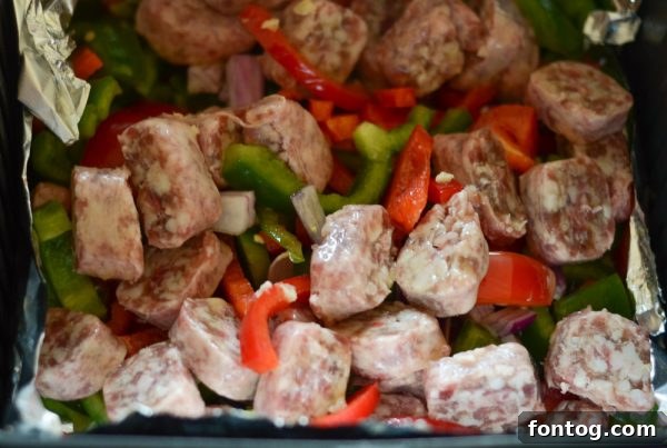 Sliced bratwurst and colorful bell peppers and onions in an air fryer basket before cooking