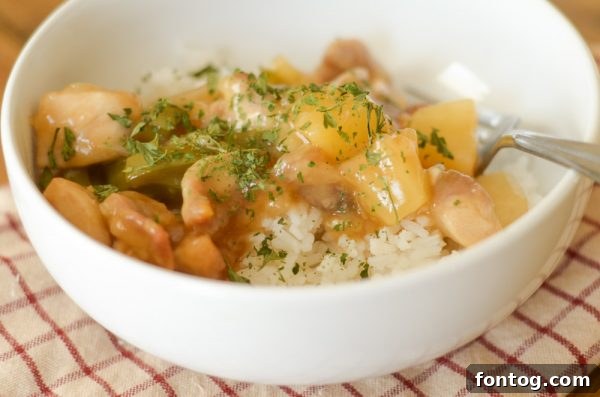 A bowl of gluten-free sweet and sour chicken, topped with fresh herbs, ready to be served.