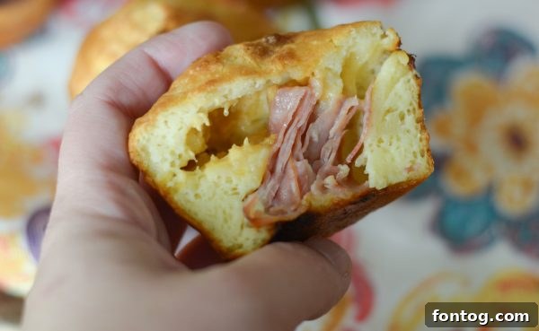 Irresistible Ham and Cheese Popovers 8 A freshly baked ham and cheese stuffed popover sliced open, revealing its fluffy interior and savory filling.