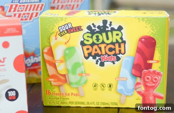 Summer Ice Pop Bash 9 Close-up of a hand holding a vibrant, multi-colored ice pop against a blurred summer background