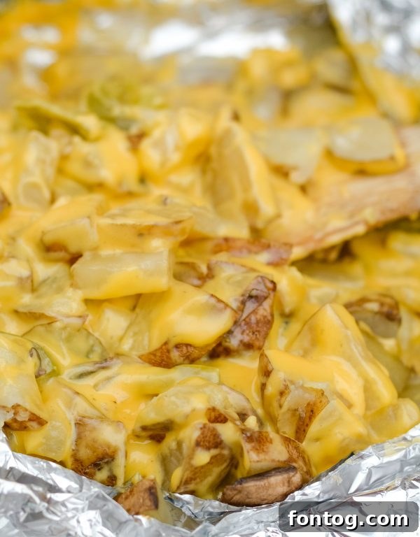 Your New Favorite Cheesy Grilled Potatoes 2 grilled cheesy potatoes, golden brown and bubbling with melted cheese, nestled in a foil packet on a grill