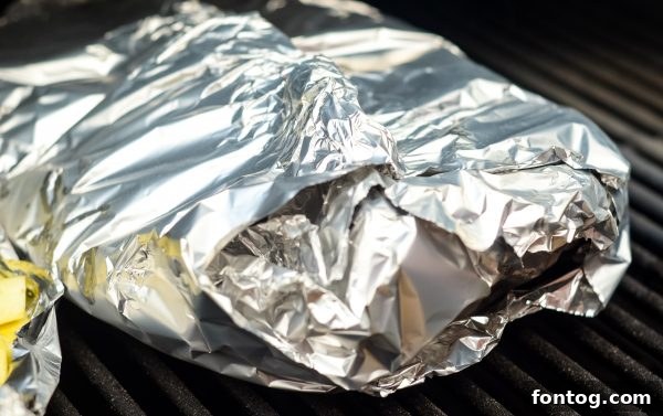 Your New Favorite Cheesy Grilled Potatoes 5 a close-up of grilled cheesy potatoes with melted Velveeta and herbs in a foil packet