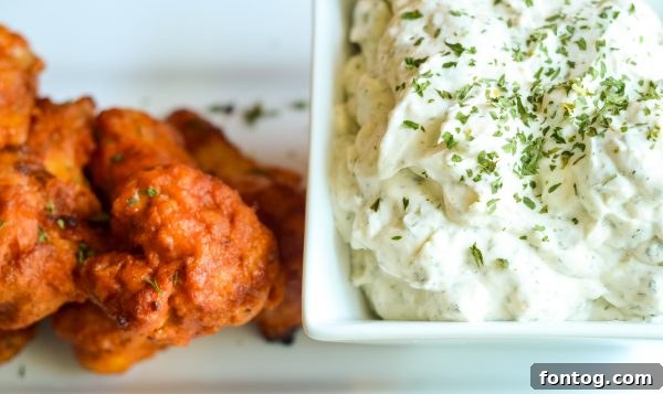 A bowl of creamy dill dip surrounded by fresh vegetables.