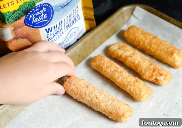 A young child confidently holding a bowl of Gorton's fish sticks, demonstrating early cooking involvement.
