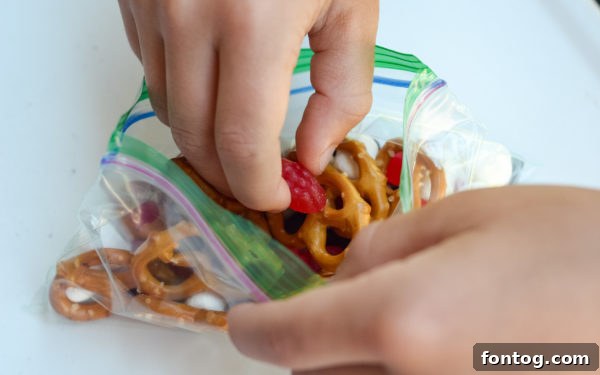 Small, portioned snack bags of No-Bake Sweet & Salty Snack Mix, ready for on-the-go enjoyment.