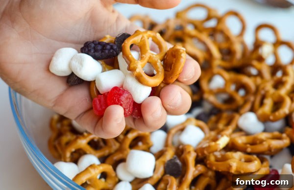 A child's hand reaching for a portion of the No-Bake Sweet & Salty Snack Mix, highlighting its kid-friendliness.